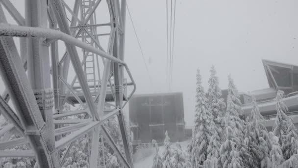Torre de góndola sobre árboles perennes cubiertos de nieve blanca durante un día de temporada de invierno nevado. — Vídeo de stock