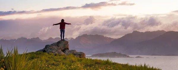 Mulher Aventurosa com as mãos em pé sobre uma rocha. Dramático céu do nascer do sol. — Fotografia de Stock