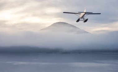 Pasifik 'in batı kıyısındaki Kanada Dağları üzerinde uçan bir deniz uçağı.