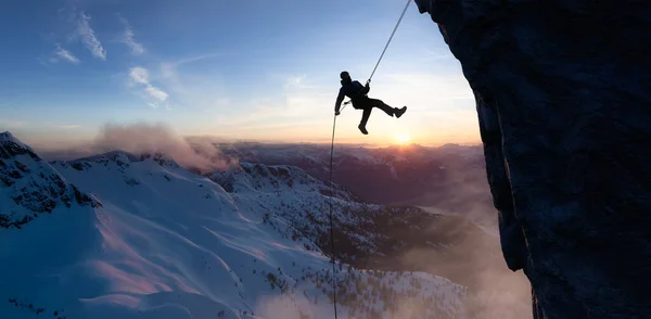 En vuxen äventyrlig man som klättrar nerför en stenig klippa. Extrema äventyr sammansatt. — Stockfoto