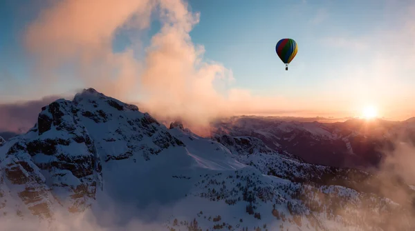Dramatische berglandschap bedekt met wolken en hete lucht ballon vliegen — Stockfoto