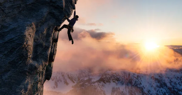 Adult adventurous man Rock Climbing a steep rocky cliff. — Stock Photo, Image