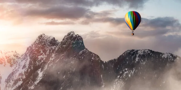 Dramatic Mountain Landscape covered in clouds and Hot Air Balloon Flying. — Stockfoto