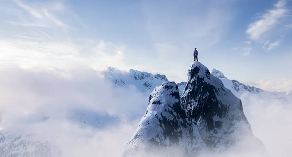Kalandos Man Tiker áll tetején jeges csúcs sziklás hegyek a háttérben. — Stock Fotó