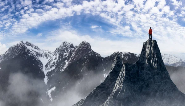 岩の多い山を背景に氷のピークの上に立つ冒険的な男のハイカー. — ストック写真