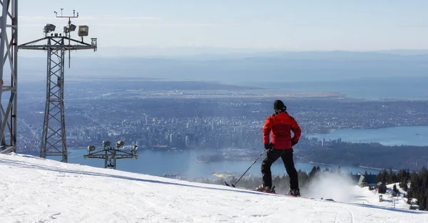 Skiier riding the snowy mountain with the city in background. Sunny morning — Stock Photo, Image