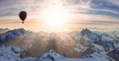 Bulutlarla kaplı dramatik Dağ manzarası ve Sıcak Hava Balonu Uçuşu.