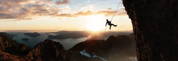 Adventurous Rock Climbing Man Sappelling down strmý rock of mountain. — Stock fotografie