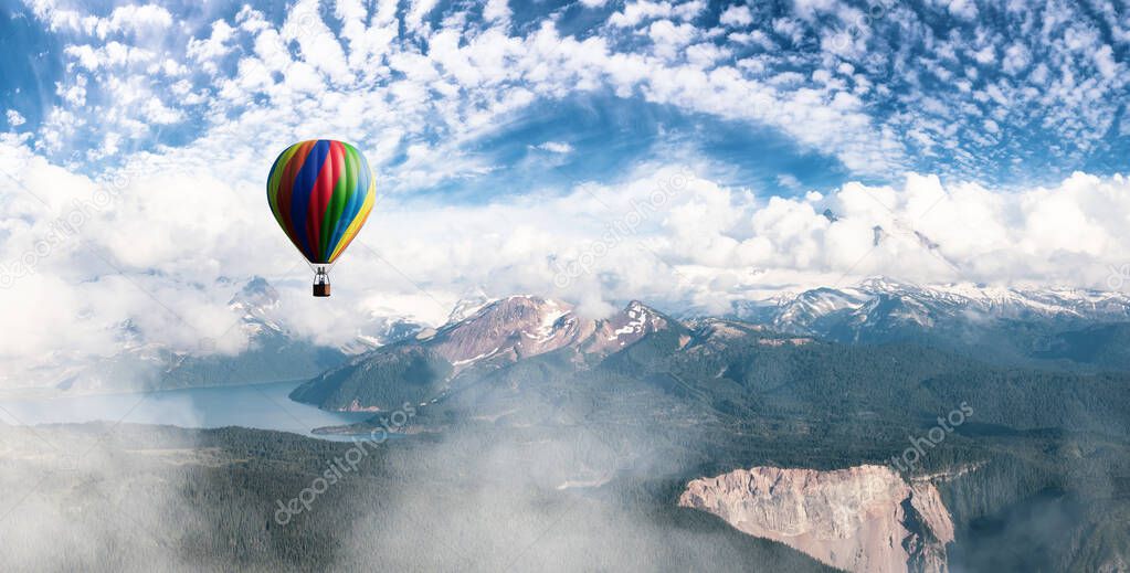 Dramatic Mountain Landscape covered in clouds and Hot Air Balloon Flying.