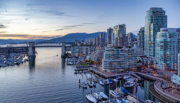 Modern şehir silueti ve arka planında dağlar olan False Creek 'in havadan görünüşü