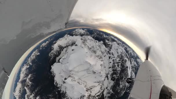 Pequeño avión de un solo motor volando sobre el paisaje de montaña rocosa cubierto de nieve. — Vídeos de Stock