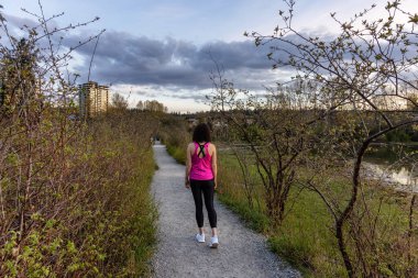 Shoreline Trail 'de Yeşil ağaçlarla Bir Yolda Yürüyen Kadın