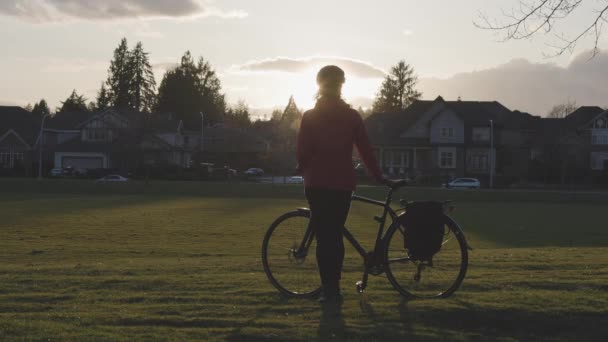 現代都市郊外の公園に自転車で立つ冒険的な女性. — ストック動画