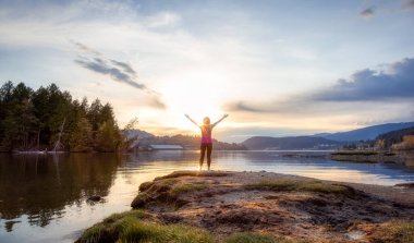 Sahildeki maceraperest kadın renkli günbatımının tadını çıkarıyor..