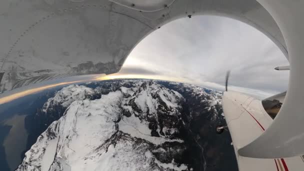 在雪地上飞行的小型单引擎飞机覆盖着岩石山景. — 图库视频影像