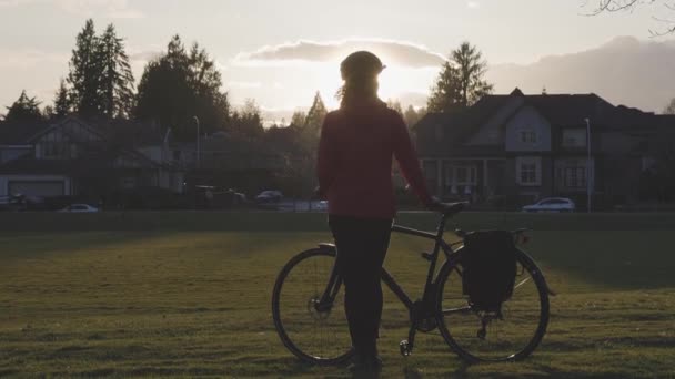 現代都市郊外の公園に自転車で立つ冒険的な女性. — ストック動画