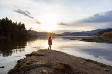 Sahildeki maceraperest kadın renkli günbatımının tadını çıkarıyor..