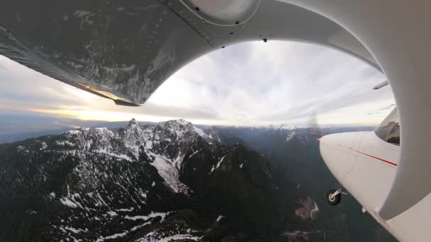 Pequeño avión de un solo motor volando sobre el paisaje de montaña rocosa cubierto de nieve. — Vídeo de stock