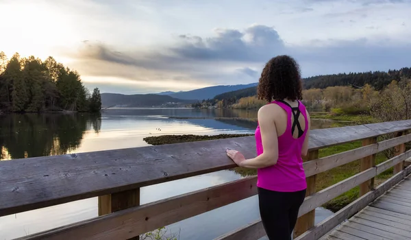 Kıyı şeridinde yeşil ağaçlarla Tahta Yol 'da Yürüyen Kadın