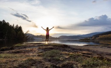 Sahildeki maceraperest kadın renkli günbatımının tadını çıkarıyor..