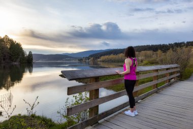 Kıyı şeridinde yeşil ağaçlarla Tahta Yol 'da Yürüyen Kadın