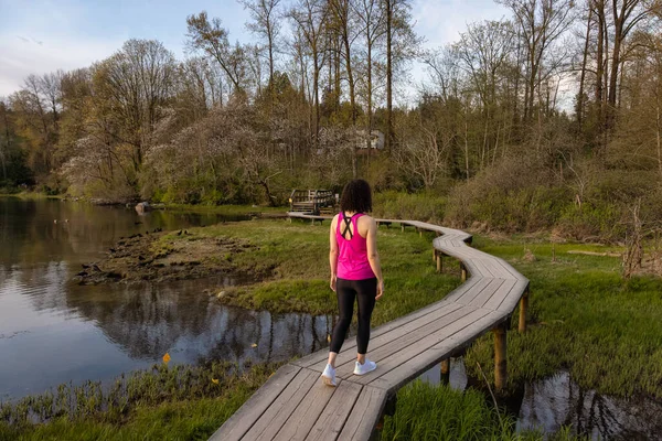 Kıyı şeridinde yeşil ağaçlarla Tahta Yol 'da Yürüyen Kadın