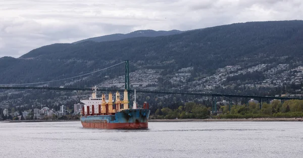 Nákladní loď připlouvá do přístavu Vancouver s mostem Lions Gate a horami v pozadí — Stock fotografie