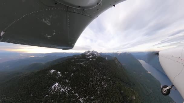 Piccolo aereo monomotore che sorvola il paesaggio montano roccioso innevato. — Video Stock