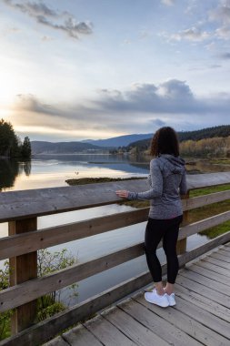 Kıyı şeridinde yeşil ağaçlarla Tahta Yol 'da Yürüyen Kadın