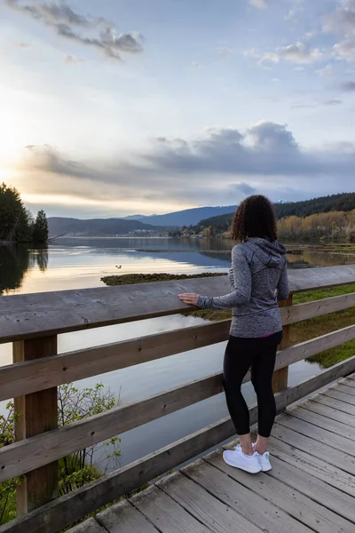 Kıyı şeridinde yeşil ağaçlarla Tahta Yol 'da Yürüyen Kadın