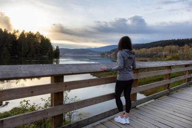 Kıyı şeridinde yeşil ağaçlarla Tahta Yol 'da Yürüyen Kadın