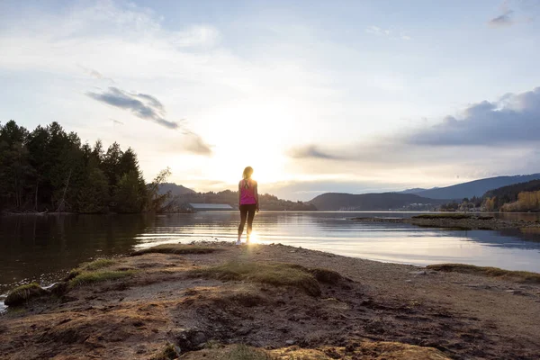 Femme aventureuse sur un rivage profitant du coucher de soleil coloré. — Photo
