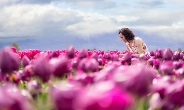 Caucasian Adult Woman looking at fresh Tulip Flowers in a field. — Stock Photo, Image