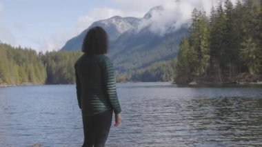 Kanada Doğa Manzarası 'nda su kenarında kayalıklarda gezen maceraperest beyaz kadın. Buntzen Gölü, Anmore, Vancouver, BC, Kanada. Macera Yolculuğu Konsepti