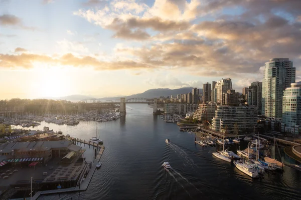 False Creek 'teki Granville Adası' nın modern şehir silueti ve arka planında dağlar olan havadan görüntüsü. Vancouver şehir merkezi, British Columbia, Kanada. Günbatımı Gökyüzü Sanatı Görüntüleyici
