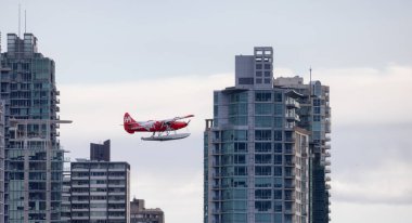 Vancouver, British Columbia, Kanada - 7 Mayıs 2022: Harbour Air Seaplane, Coal Harbour 'dan ayrılıyor. Bulutlu Gökyüzü ve arka plandaki modern şehir binaları.