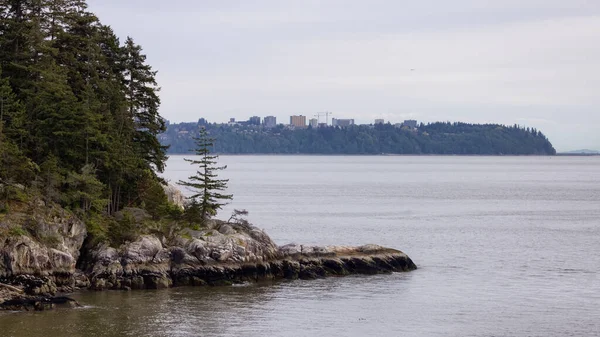 Pasifik Okyanusu 'nun batı kıyısında Rocky Shore ve Arka planda UBC. Horseshoe Körfezi, Batı Vancouver, British Columbia, Kanada.