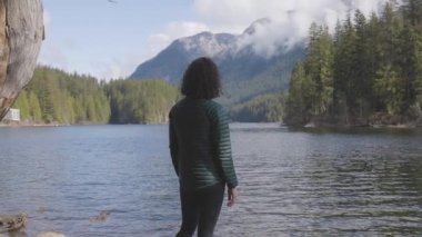 Kanada Doğa Manzarası 'nda su kenarında kayalıklarda gezen maceraperest beyaz kadın. Buntzen Gölü, Anmore, Vancouver, BC, Kanada. Macera Yolculuğu Konsepti