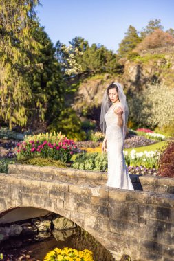 White Caucasian Adult Woman in a Wedding Dress standing outside in nature. Queen Elizabeth Park, Vancouver, British Columbia, Canada. Bride