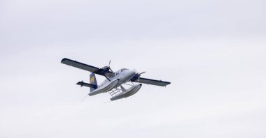 Vancouver, British Columbia, Kanada - 7 Mayıs 2022: Harbour Air Seaplane, Coal Harbour 'dan ayrılıyor. Bulutlu Gökyüzü Arkaplanı.