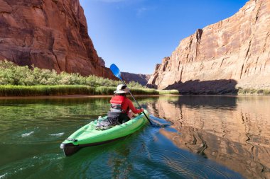 Colorado Nehri 'nde Kano kürek çeken maceraperest bir kadın. Glen Canyon, Arizona, Amerika Birleşik Devletleri. Amerikan Dağları Doğa Manzarası Arkaplanı. Macera Yolculuğu