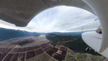 Pitt Meadows üzerinde uçan küçük tek motorlu uçak. Bulutlu bir kış akşamı. Geniş Açı Balık Gözlü Lens. Büyük Vancouver, İngiliz Kolombiyası, Kanada.