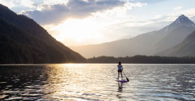Maceracı Kadın Kanada Dağları 'nın etrafındaki bir gölde yüzüyor. Chilliwack Gölü, British Columbia, Kanada. Macera Spor Seyahati