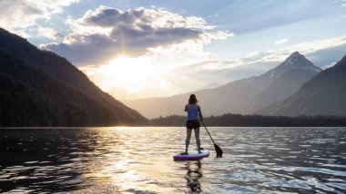 Adventurous Woman Paddle Boarding in a Lake around Canadian Mountain Landscape. Chilliwack Lake, British Columbia, Canada. Adventure Sport Travel