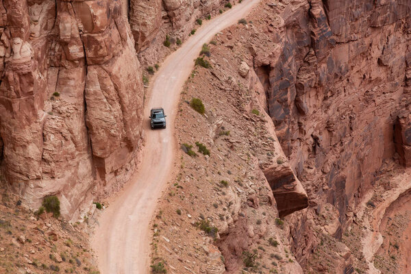 Truck riding on Scenic Dirt Road surrounded by Red Rock in Desert Canyon. Spring Season. Canyonlands National Park. Utah, United States. Adventure Travel.