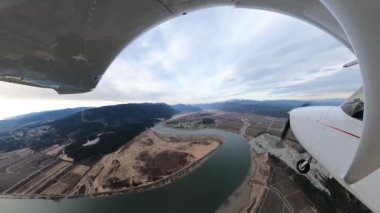Small Single Engine Airplane flying over Pitt Meadows. Cloudy winter evening. Wide Angle Fish Eye Lens. Greater Vancouver, British Columbia, Canada.