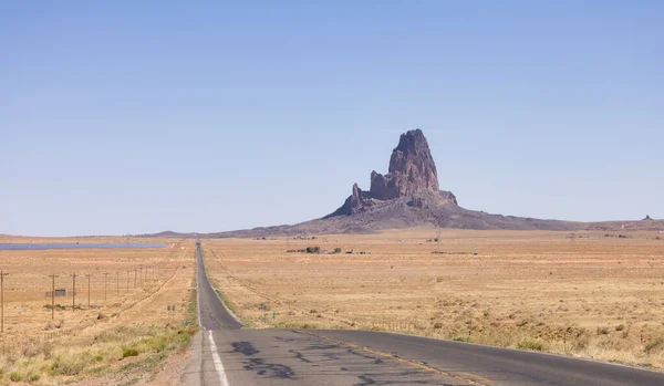 Scenic Road in the Dry Desert with Red Rocky Mountains in Background. Oljato-Monument Valley, Arizona, United States.