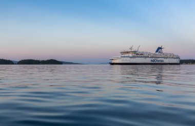 Victoria, Vancouver Island, British Columbia, Canada - July 13, 2022: BC Ferries Boat leaving the Terminal in Swartz Bay during colorful summer sunset.