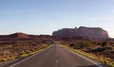 Scenic Road in the Dry Desert with Red Rocky Mountains in Background. Oljato-Monument Valley, Utah, United States.