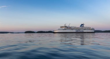 Victoria, Vancouver Island, British Columbia, Canada - July 13, 2022: BC Ferries Boat leaving the Terminal in Swartz Bay during colorful summer sunset.